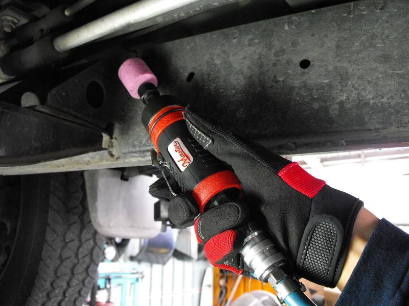 a mechanic's glove holding a wrench under a vehicle