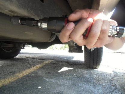 a close up of a person holding a wrench under a vehicle