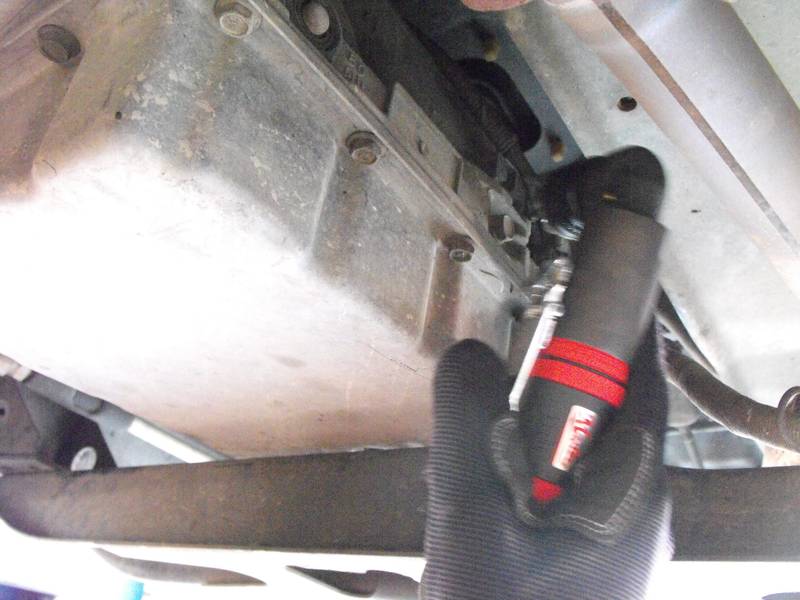 a close up of a person holding a wrench under a vehicle