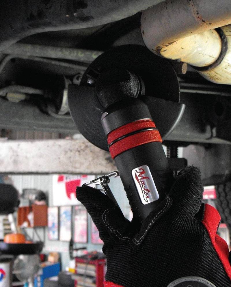 a close up of a person holding a wrench under a vehicle