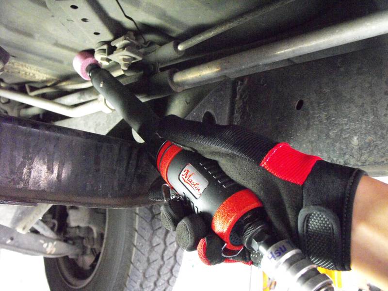 a close up of a person holding a wrench under a vehicle